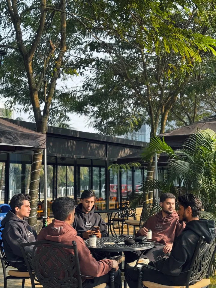 Five friends wearing FAZAL hoodies around a cafe table