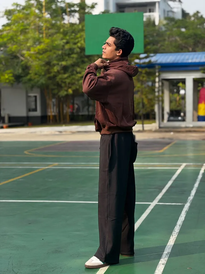 Side profile of the brown FAZAL hoodie on an outdoor court