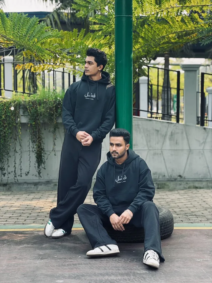 Models in black FAZAL hoodie sets resting on tyres