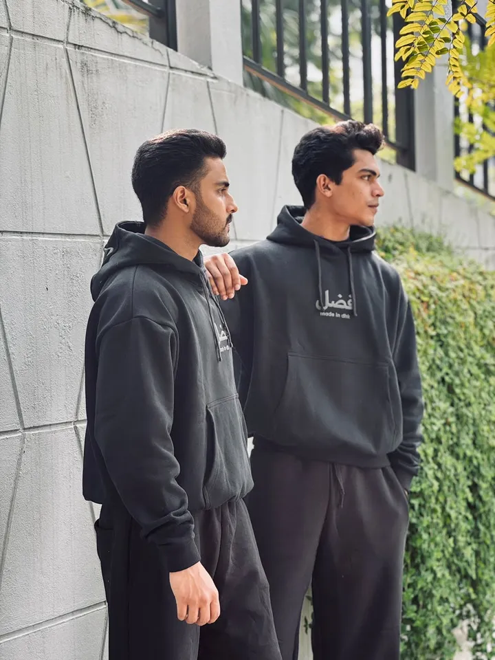 Two models against a concrete wall in black FAZAL hoodies
