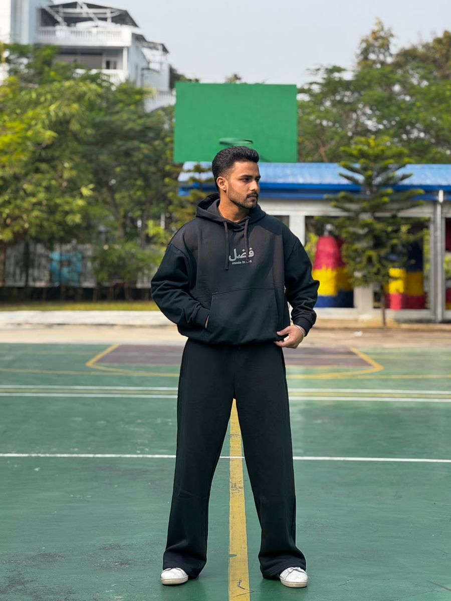 Model in the Obsidian black FAZAL hoodie and wide-leg trouser, outdoor court in Dhaka